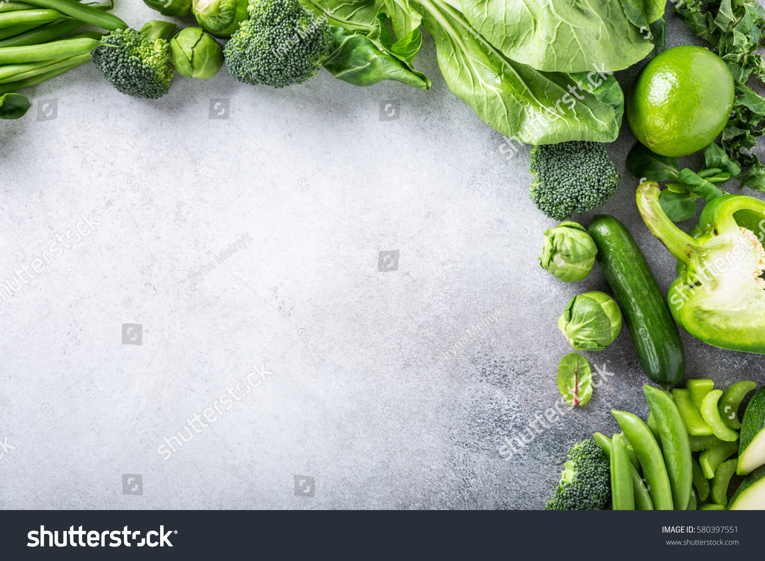 Background with assorted green vegetables, salad, broccoli, cucumber, peas and Brussels sprouts on light gray stone table top. Healthy food concept with copy space. #580397551