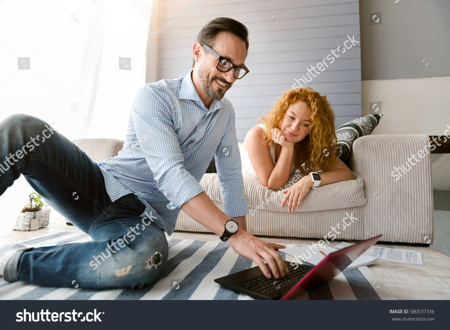 Energetic couple sitting and using laptop at home #580537336