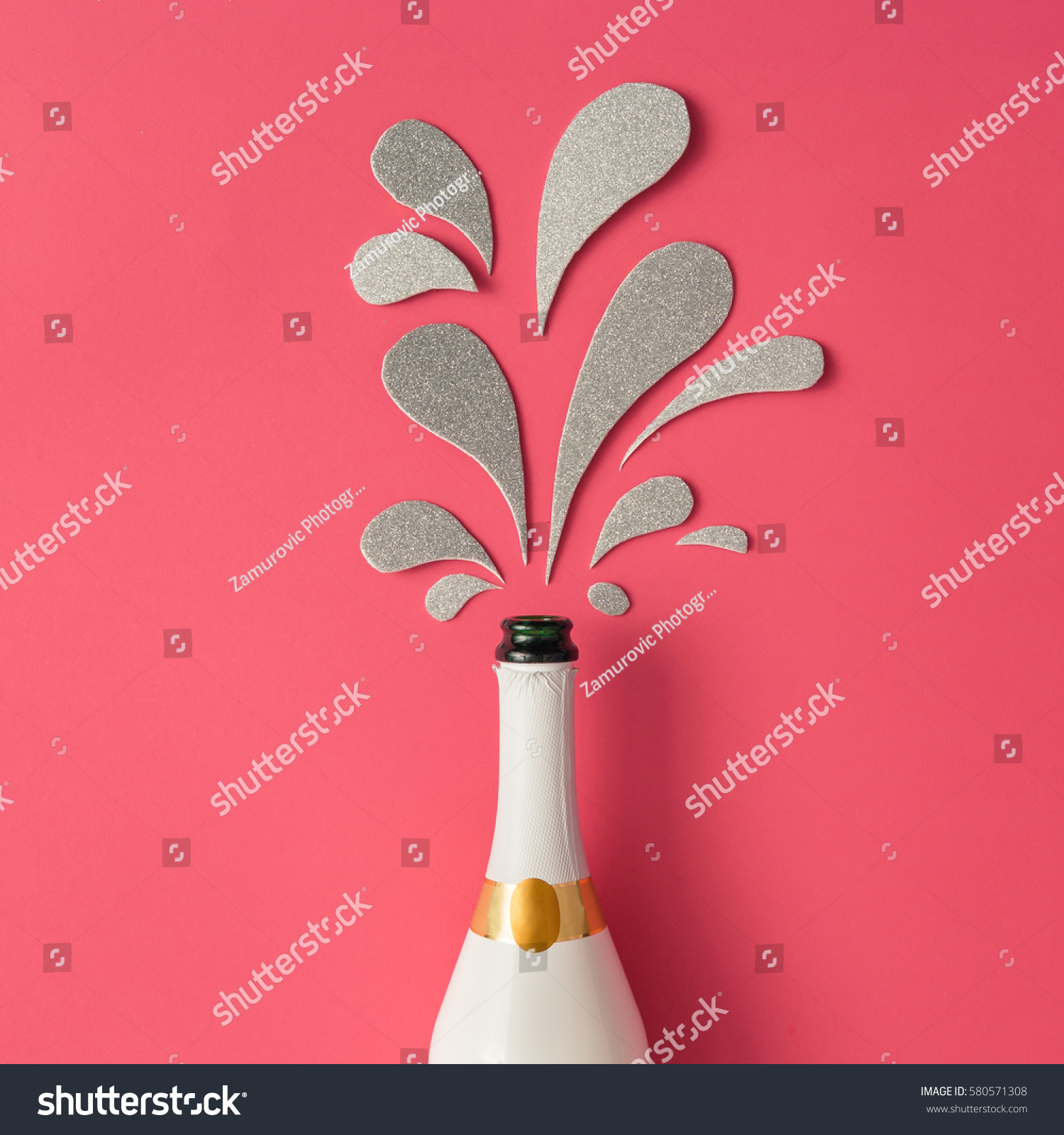 White champagne bottle with silver glittering splashes on pink background. Flat lay. Minimal party concept. #580571308