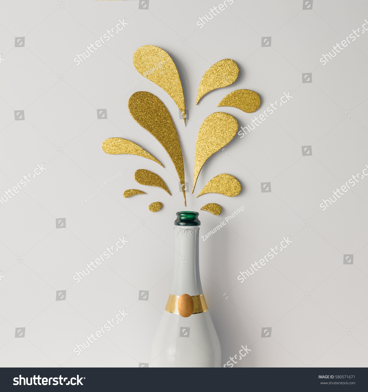 Champagne bottle with golden glittering splashes on white background. Flat lay. Minimal party concept. #580571671