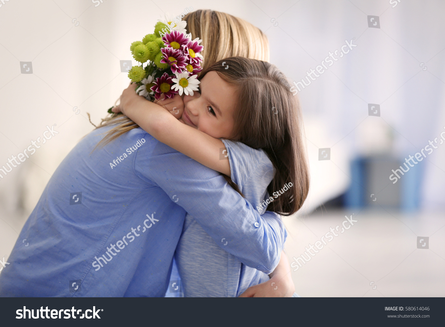 Cute little girl greeting her mother at home. Mother's day concept #580614046