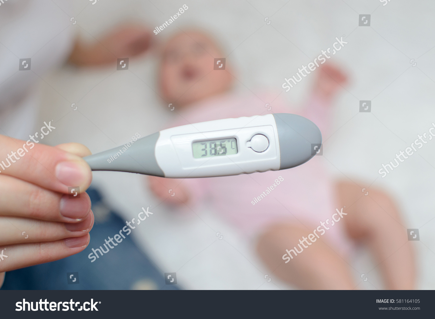 female hand holding a thermometer with high temperature on the background of a sick child #581164105