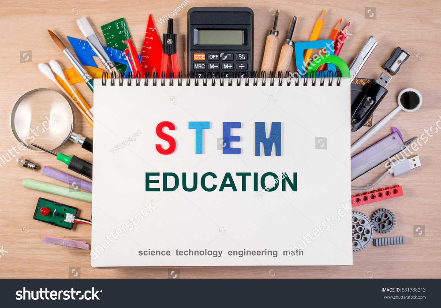 STEM education text on notebook over school supplies or office supplies on school table. Background with school or office material with copy space for text. #581788213