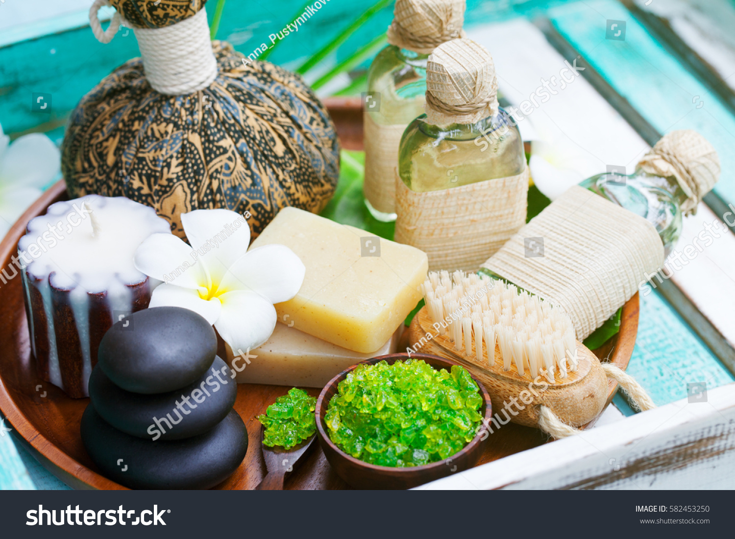 Spa and wellness massage setting. Still life with candle, towel and stones. Outdoor summer background. #582453250