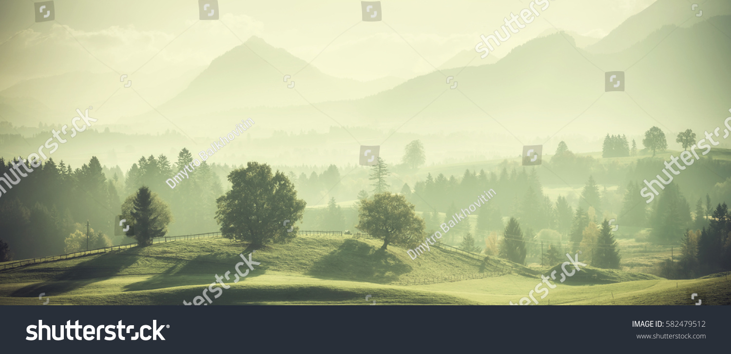 Vintage landscape with trees on hills and beautiful mountains in distance. Retro film filter #582479512