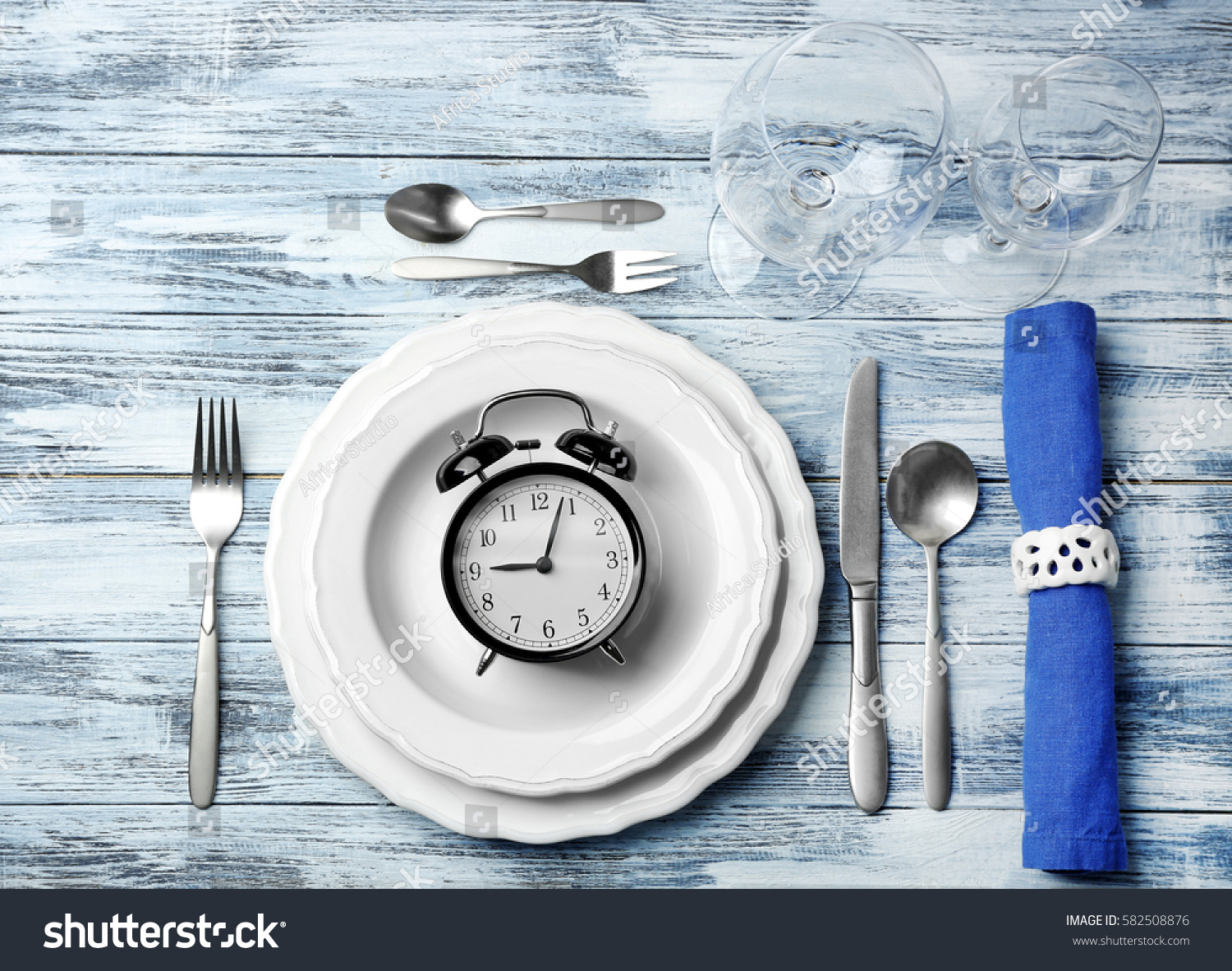 Alarm clock in empty plate on wooden background #582508876