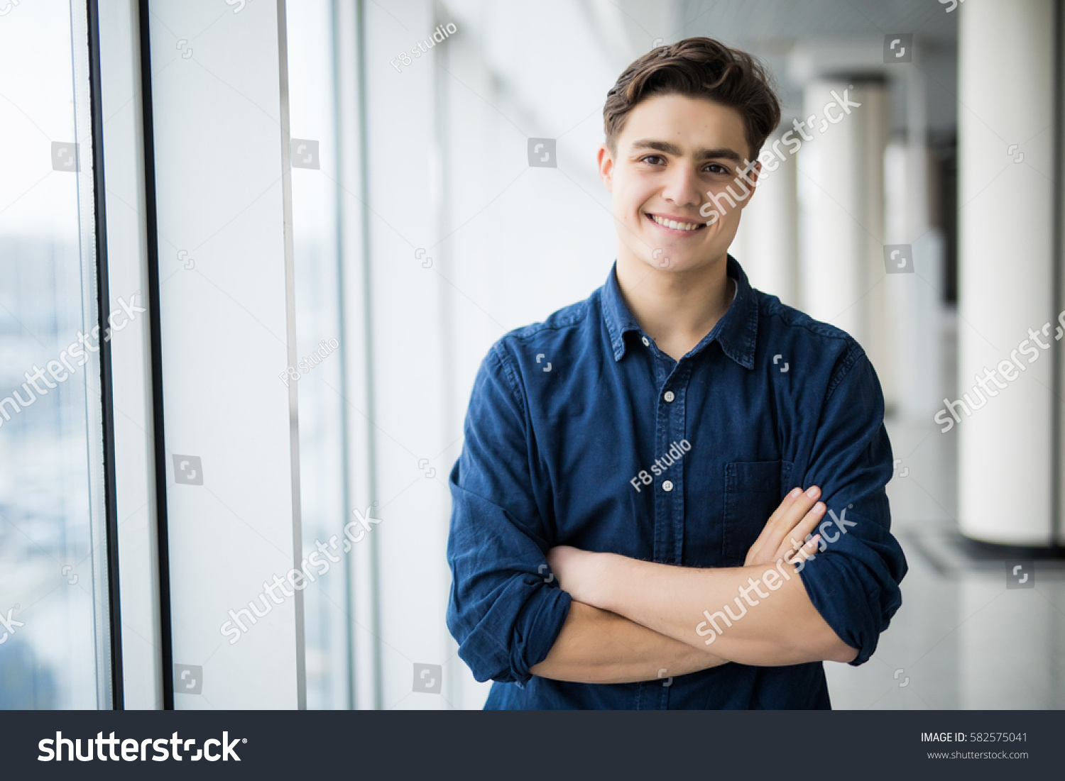 Portrait of young man with crossed hands near in window. #582575041