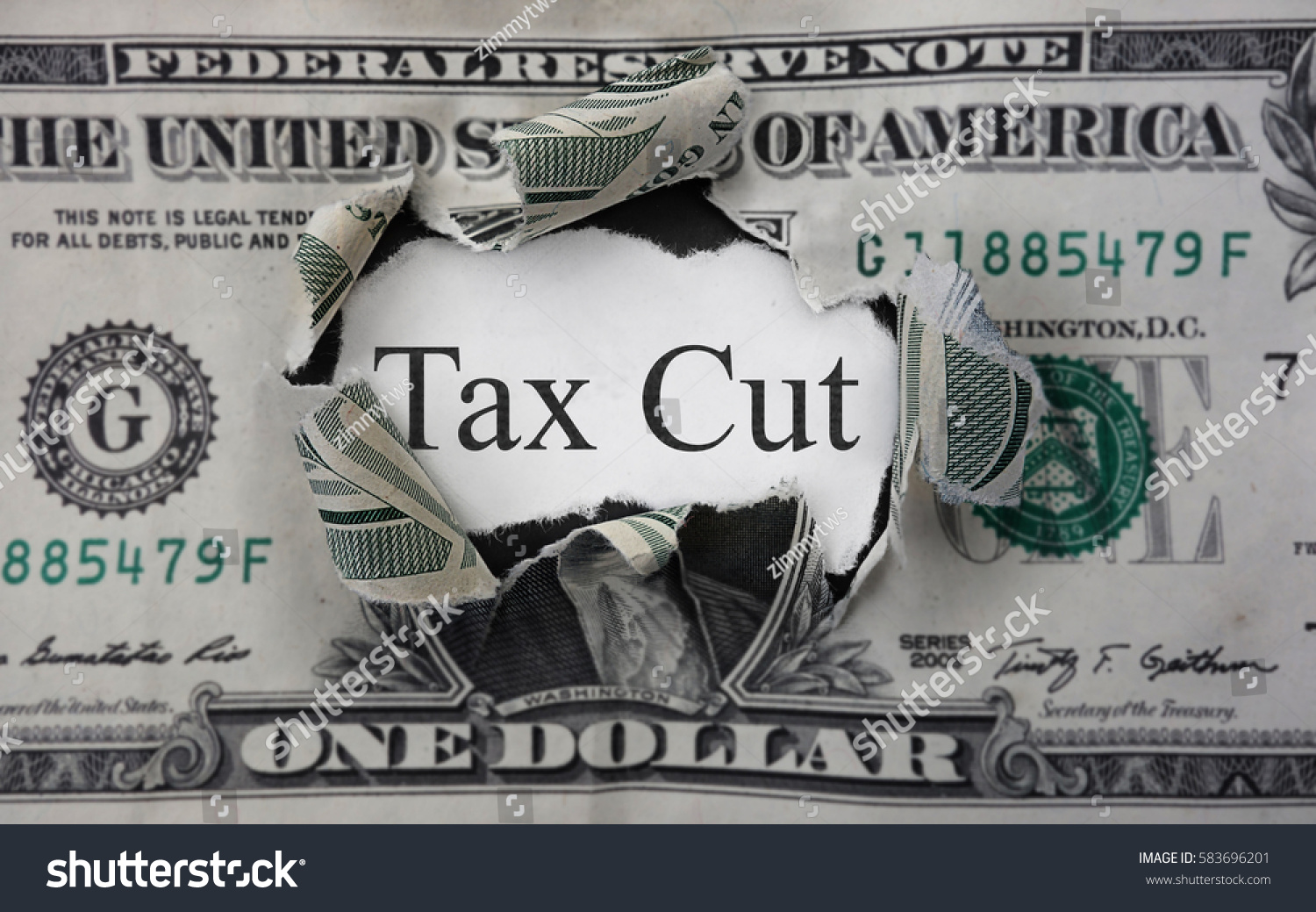 Tax Cut text on a scrap of paper within a torn dollar bill                                #583696201