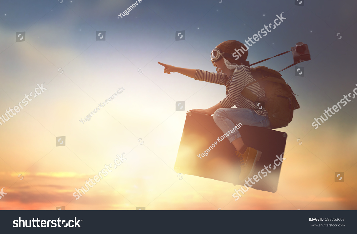 Dreams of travel! Child flying on a suitcase against the backdrop of sunset. #583753603