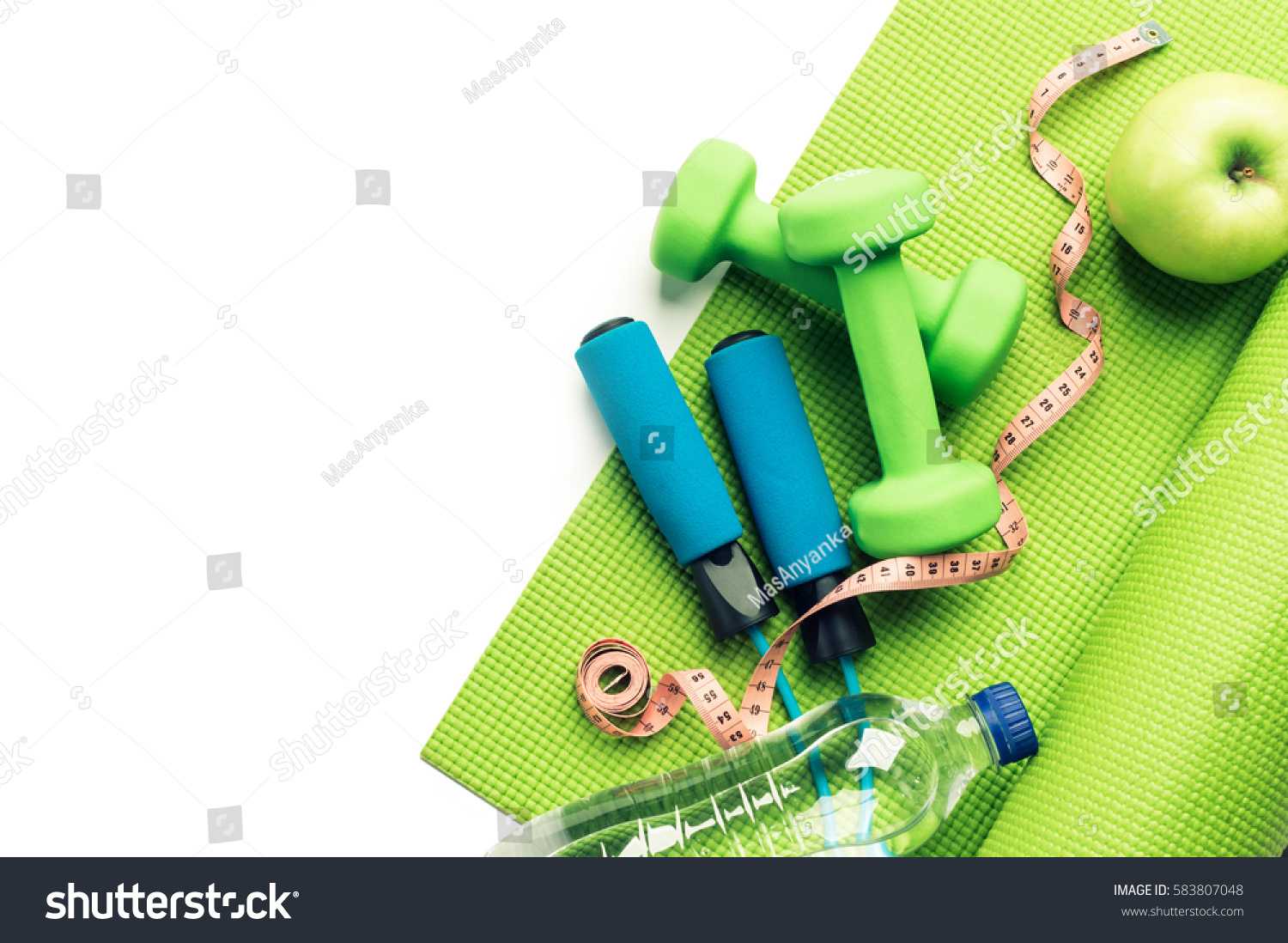 Fitness concept - yoga mat, apple, dumbbells and skipping rope on the white background #583807048