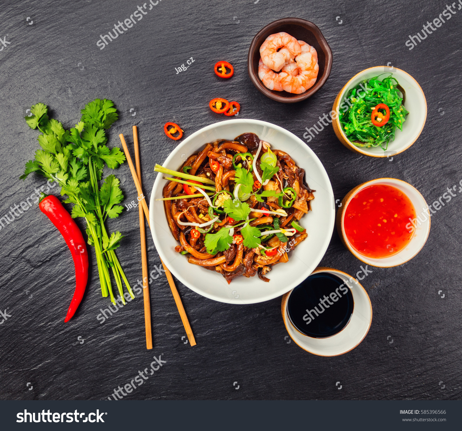 Asian noodles with spicy soy sauce and chicken pieces, top view, served on black stone. #585396566