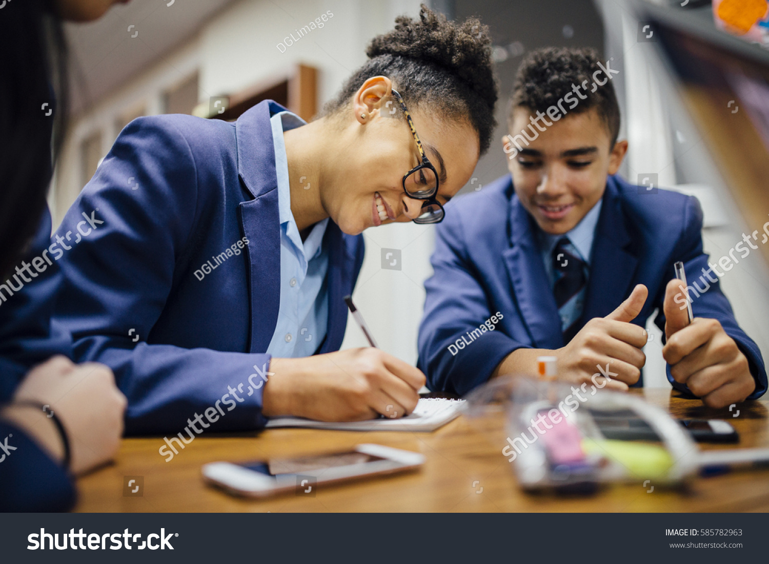Teen students are working together and taking notes in lesson time at school.  #585782963