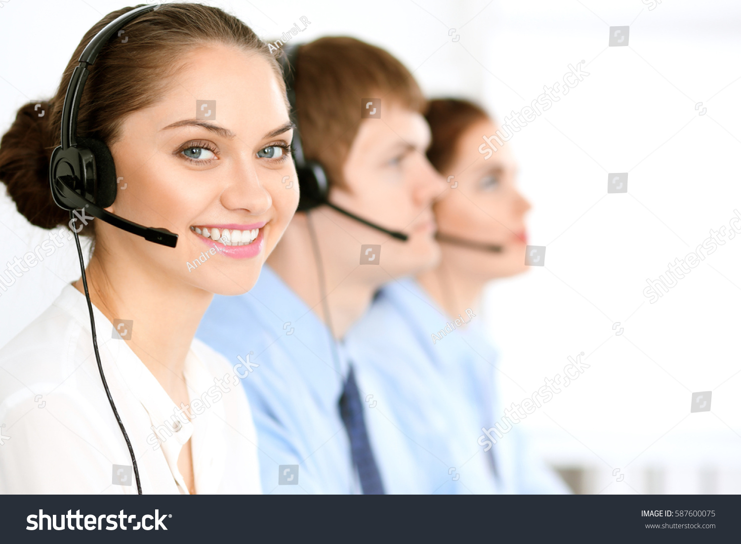Call center operators. Focus at brunette business woman in headset #587600075