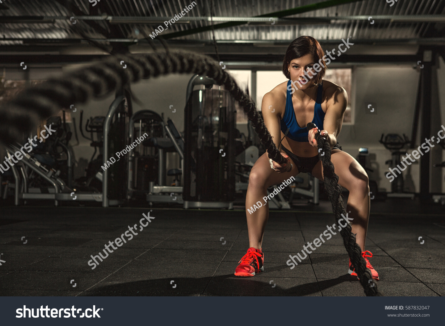 Battle ropes session. Attractive young fit and toned sportswoman working out in functional training gym doing crossfit exercise with battle ropes copyspace battling ropes cross-fit workout motivation #587832047