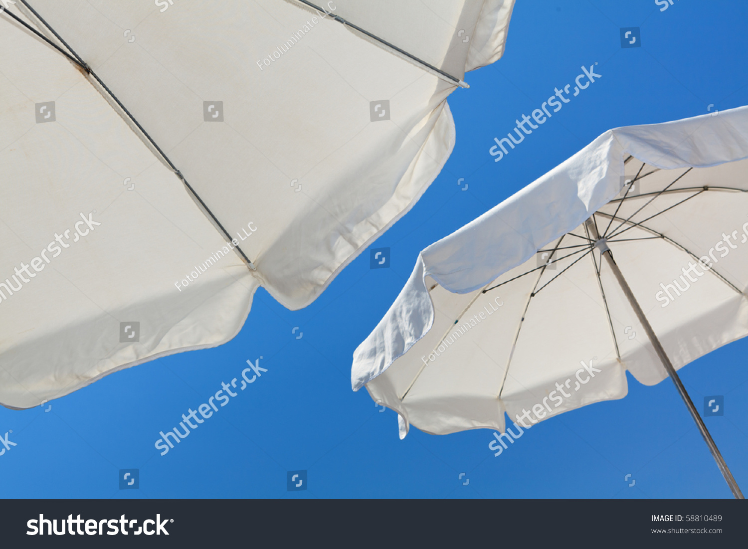 White beach umbrellas against a blue sky in the French Riviera in Nice, France. #58810489