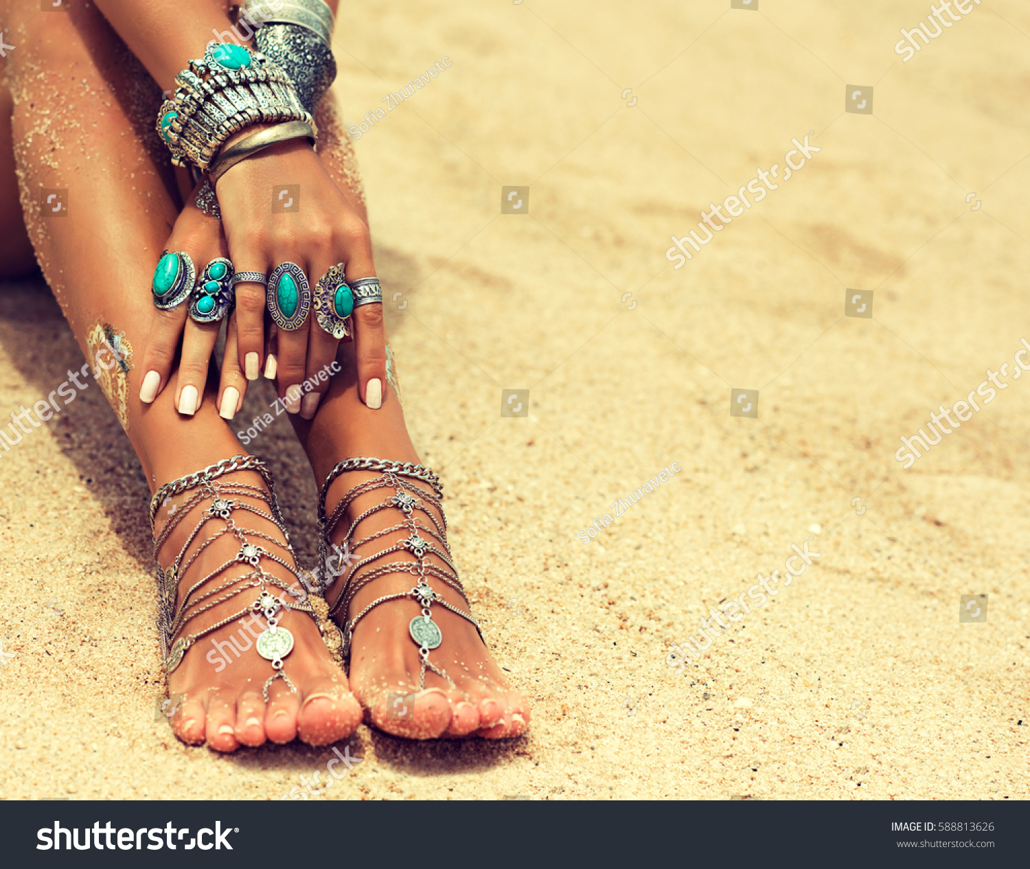 Woman In Relaxation On Tropical Beach with sand , body parts  . Tanned girl in Lotus position with silver jewelry,bracelets and rings with turquoise.Boho style #588813626