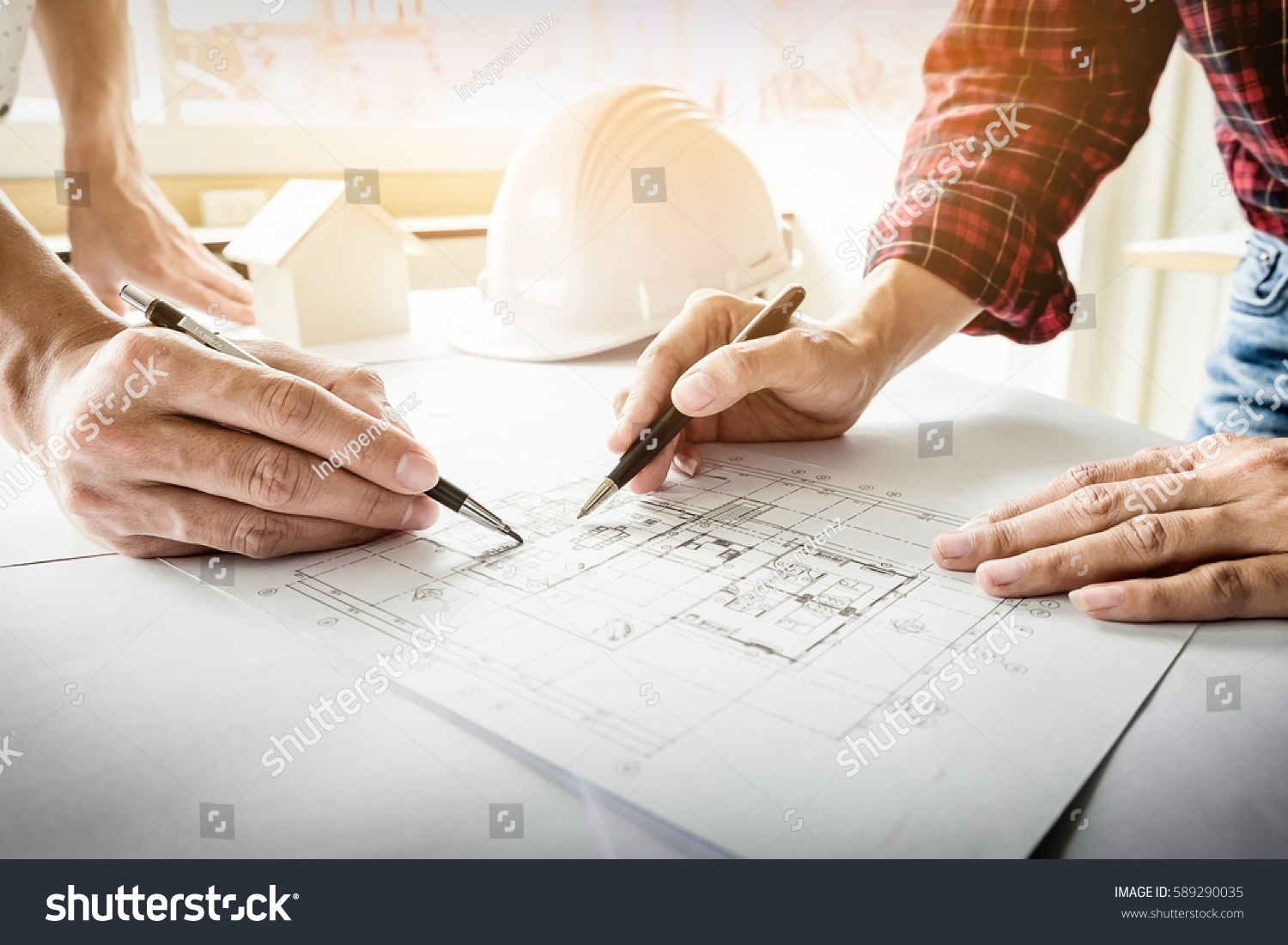 Architects engineer discussing at the table with blueprint - Closeup on hands and project print #589290035