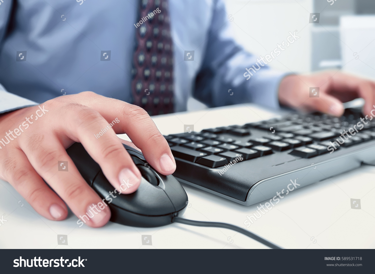 Businessman using computer with hands typing on a keyboard in the office #589531718
