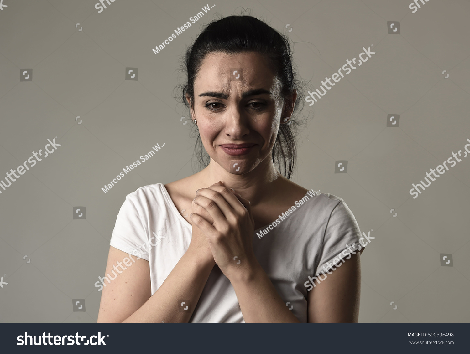 beautiful face of sad woman crying desperate and depressed with tears on her eyes suffering pain and depression isolated on grey background in sadness facial expression and emotion concept #590396498