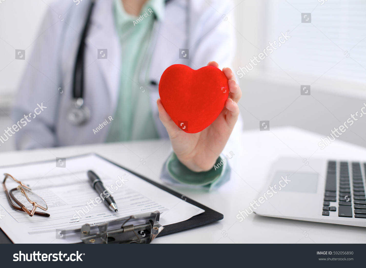 Female doctor with stethoscope holding heart.   Cardio therapeutist, physician make cardiac physical, heart rate measure, arrhythmia, old age life concept #592056890