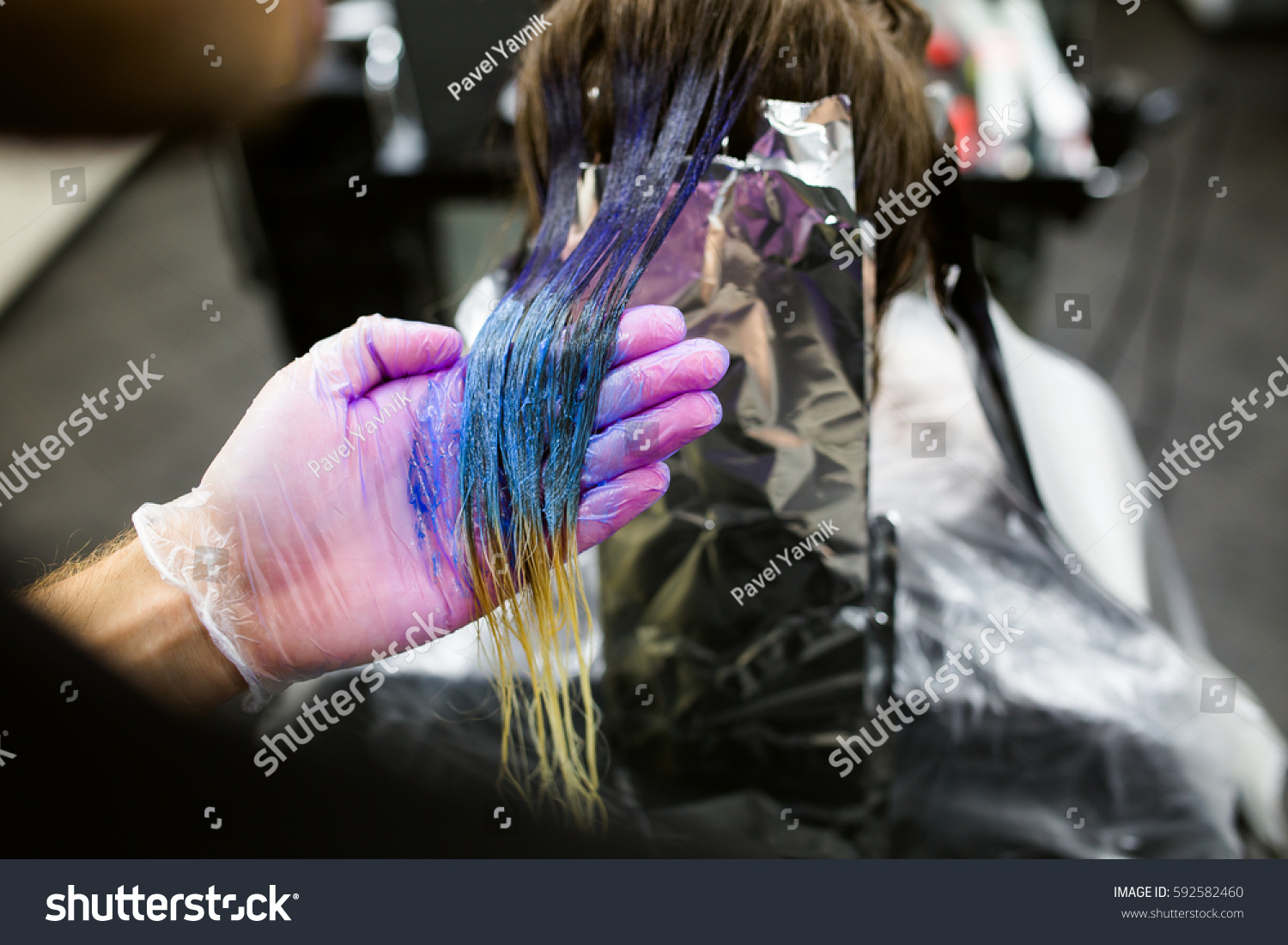 Man in gloves is dying long blue hair colorfull with brush. Beauty salon, Barber. Close-up. not recognized #592582460