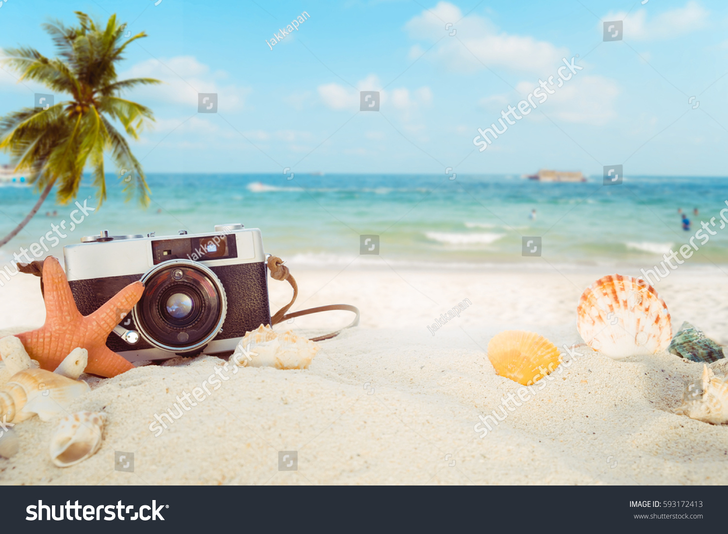 The concept of leisure travel in the summer on a tropical beach seaside. retro camera on the sandbar with starfish, shells, coral on sandbar and blur sea background.  vintage color tone styles. #593172413