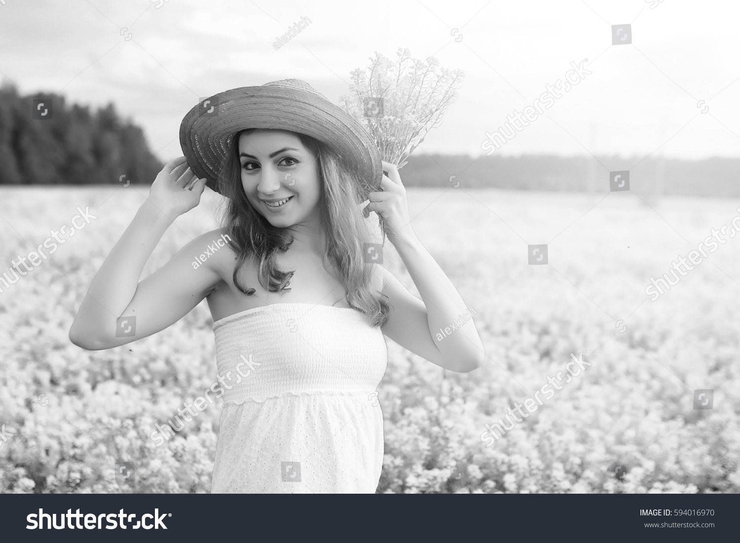 monochrome portrait of young girl in a hat standing in huge field of flowers
 #594016970