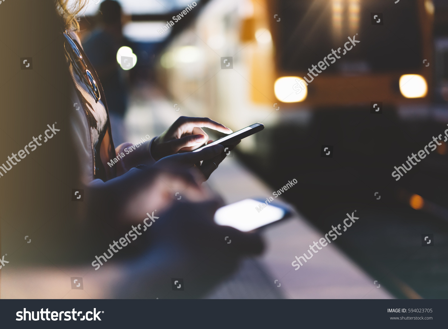 Enjoying travel. woman waiting on station platform on background light electric moving train using smart phone in night. Tourist texting message and plan route of stop railway, railroad transport #594023705