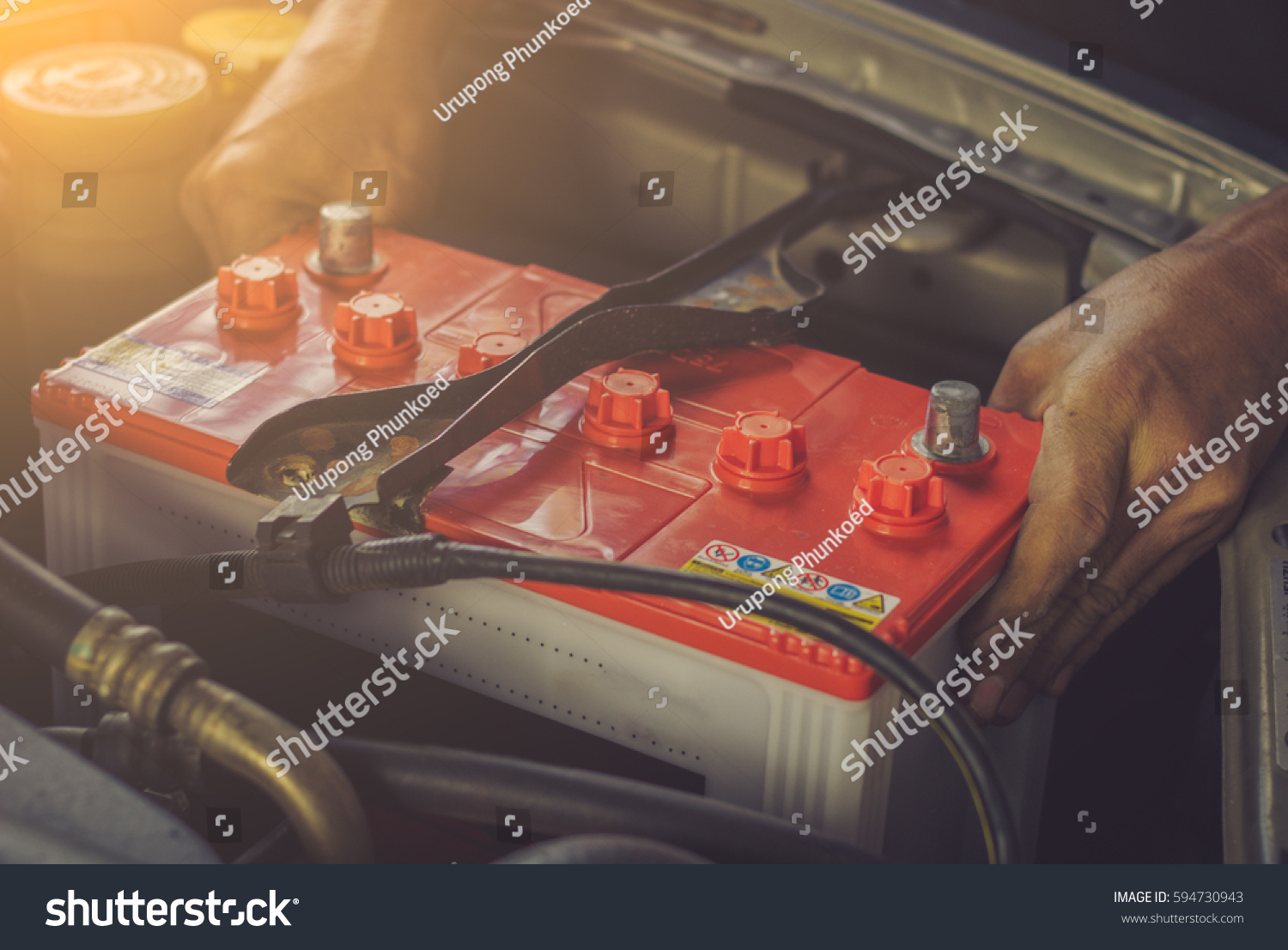 A car mechanic replaces a battery / soft focus picture  #594730943