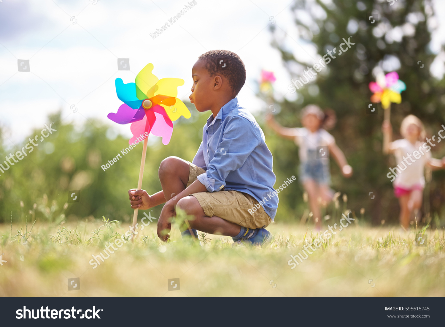African boy and friends with pinwheels playing at the park #595615745