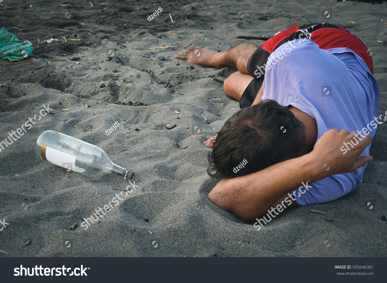 Drunk man sleeping on the sand at the beach #595646381