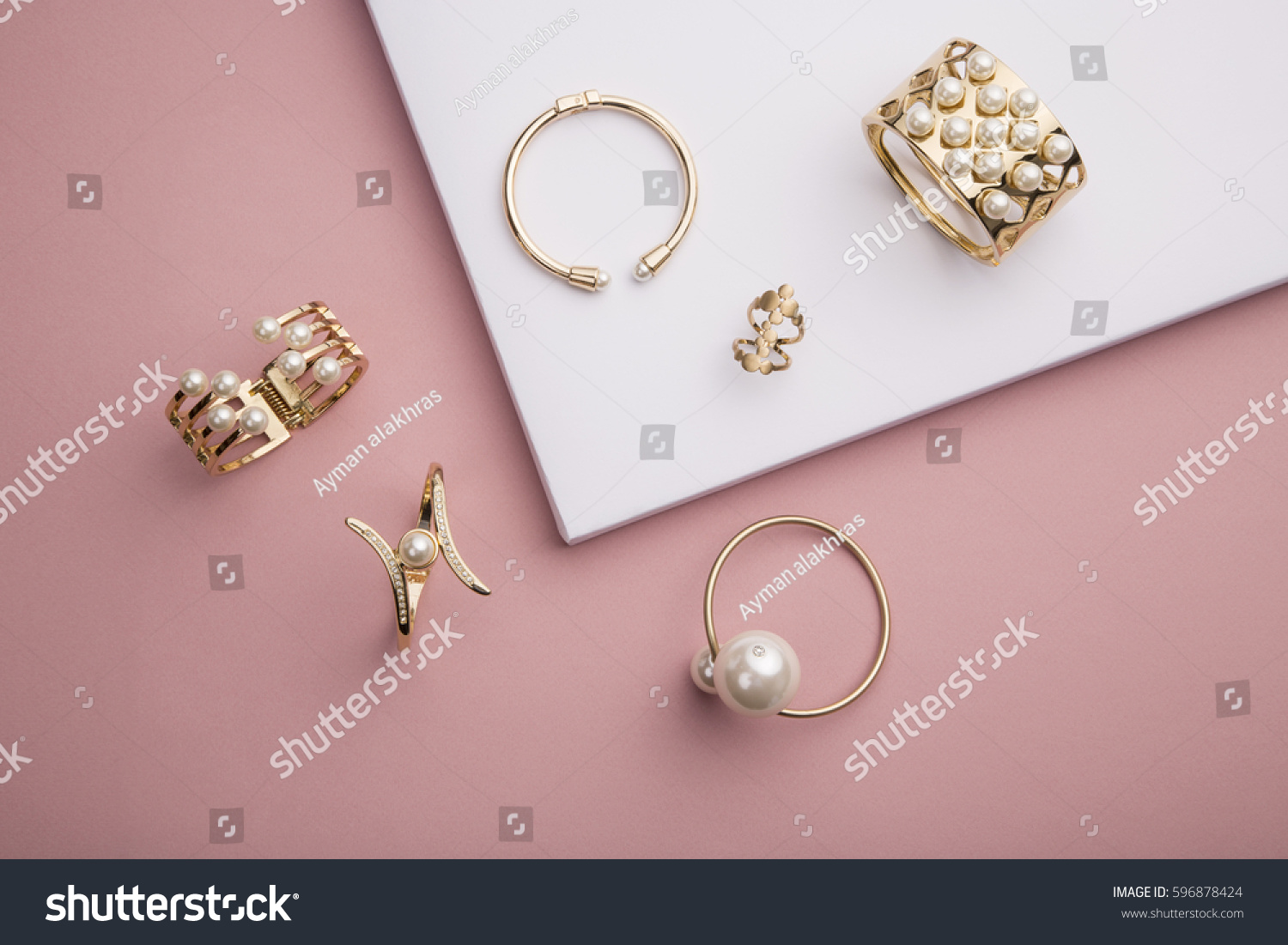 Pearl Golden Bracelets and ring on pink background - Pearl Bracelets on paper background setup  #596878424