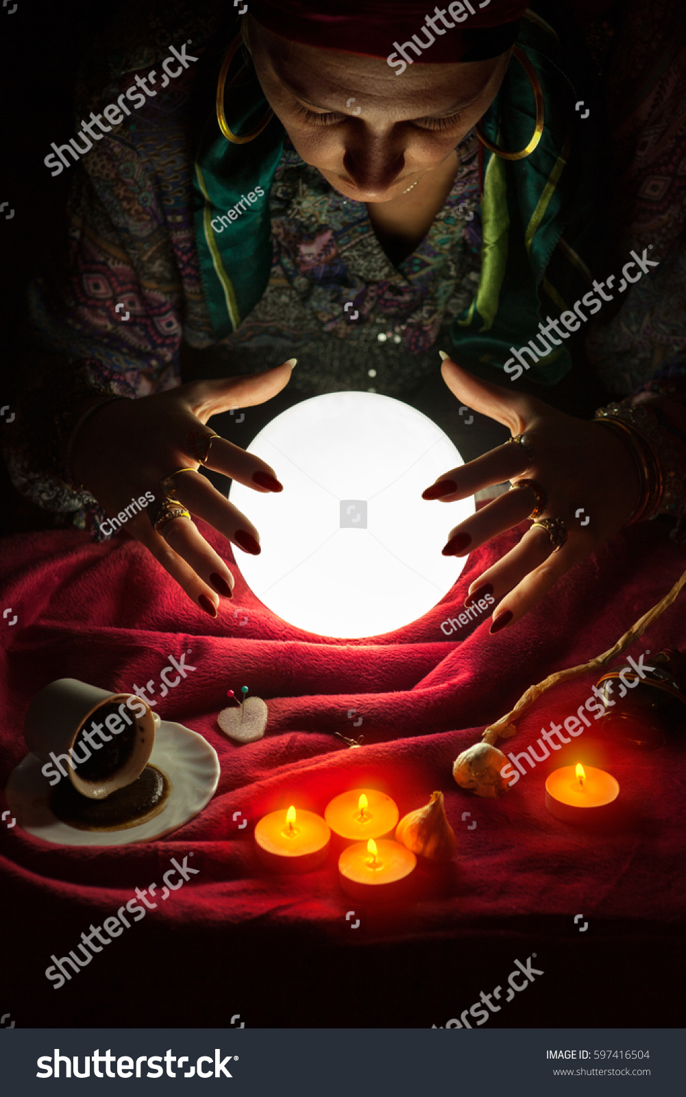 Female fortuneteller with her hands above lighted crystal ball #597416504