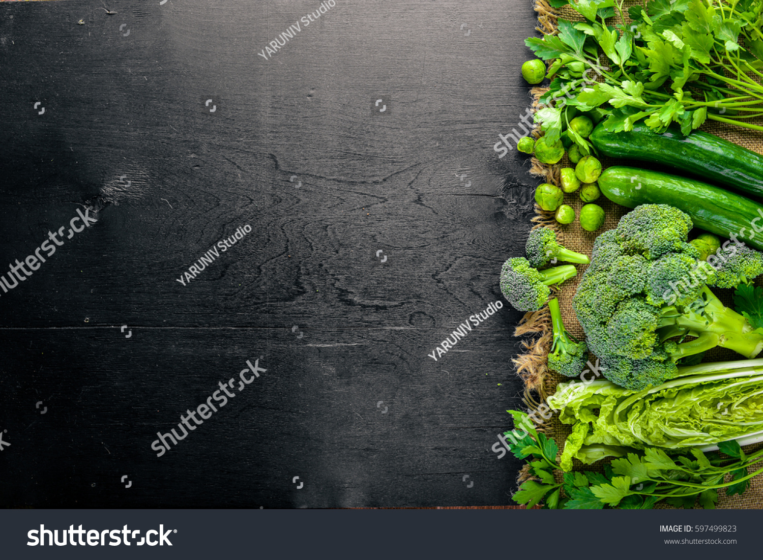 Collection of fresh green vegetables placed on black stone #597499823