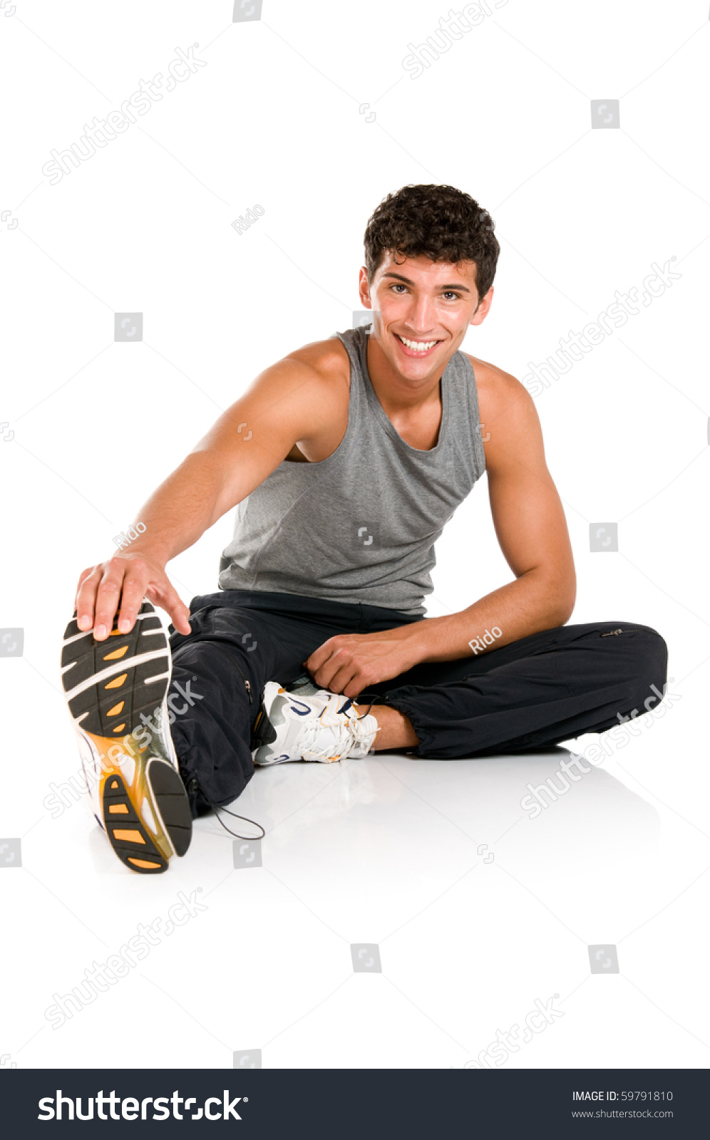 Happy smiling young fitness man sitting and making stretching exercises after gym isolated on white background #59791810