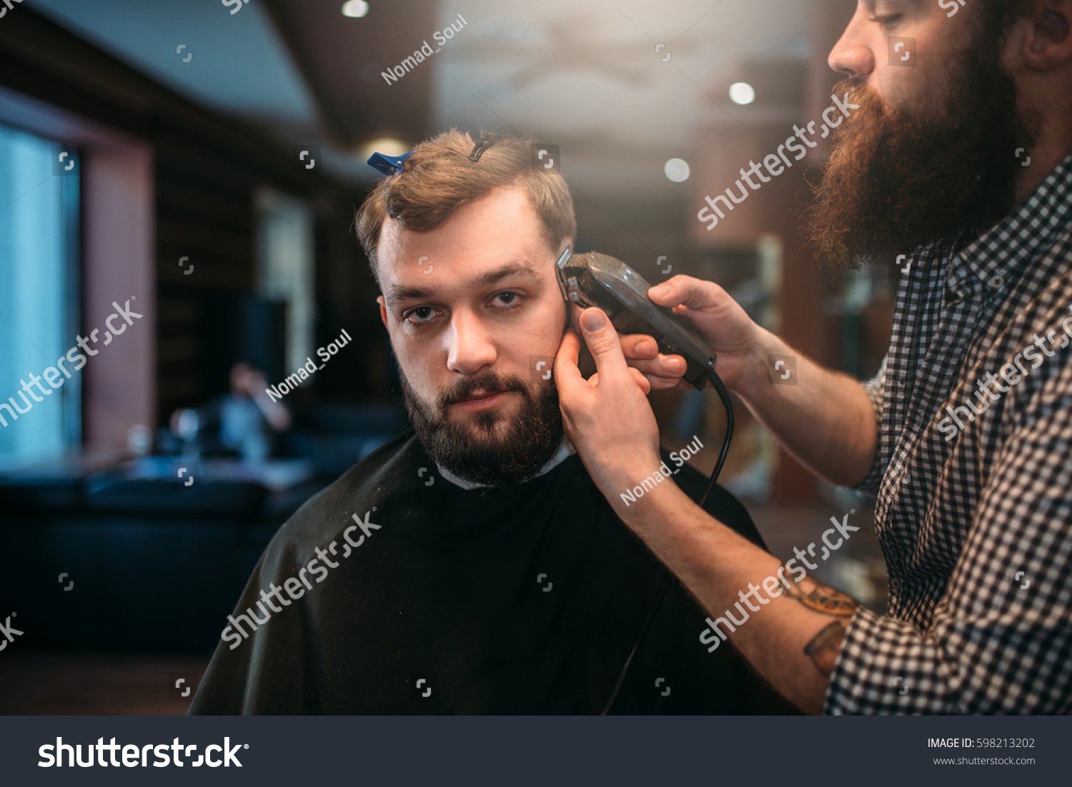 Barber trimming hair of the client man by clipper #598213202