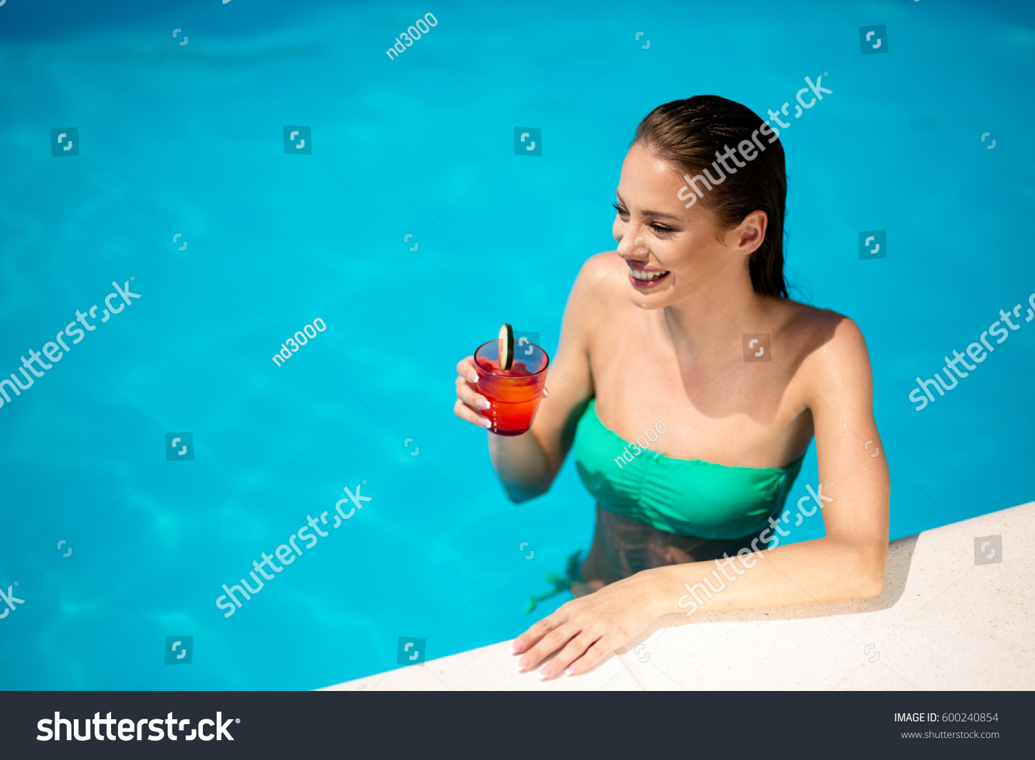 Beautiful woman drinking cocktail and sunbathing at pool #600240854