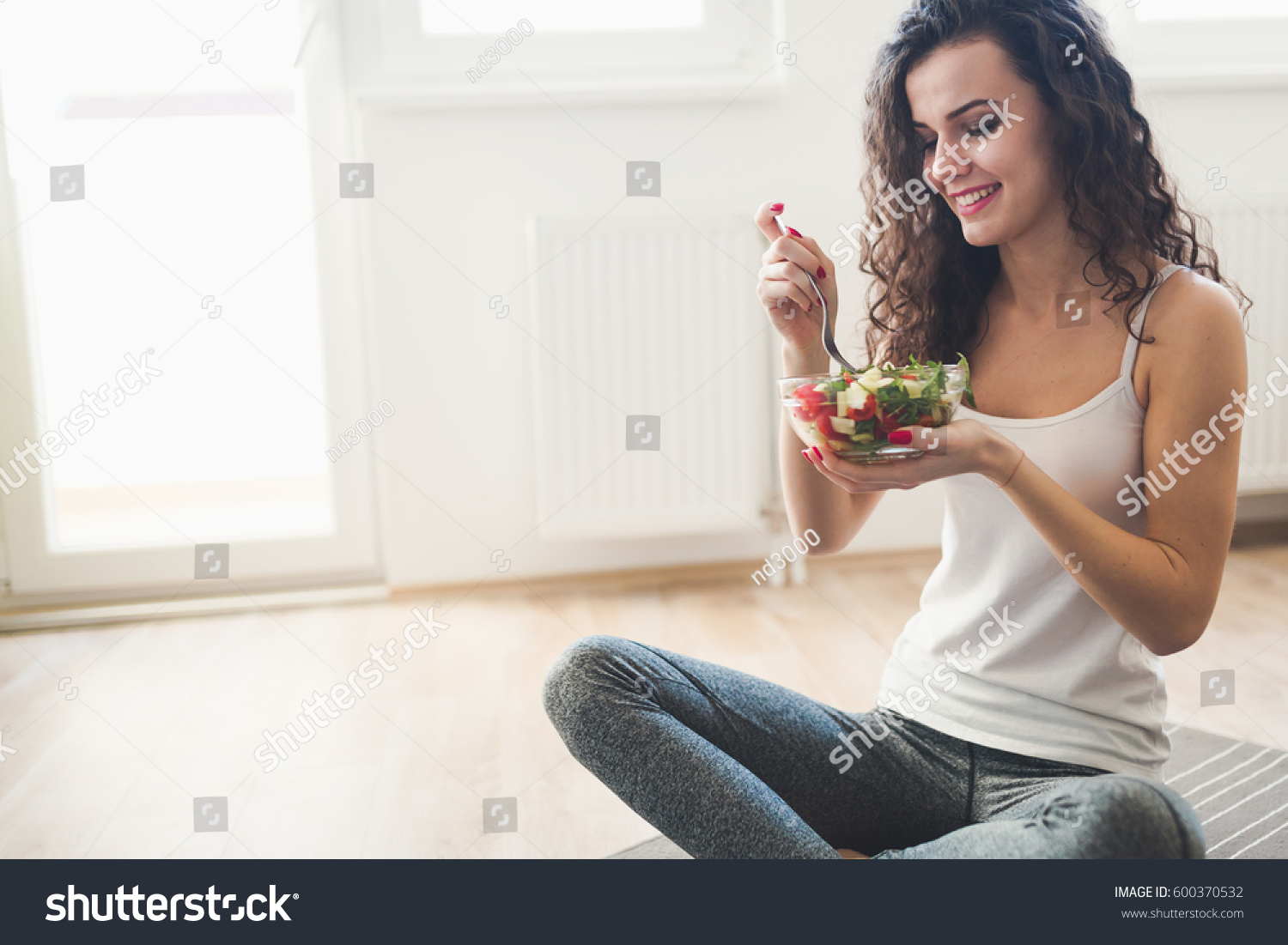 Beautiful fit woman eating healthy salad after fitness workout #600370532