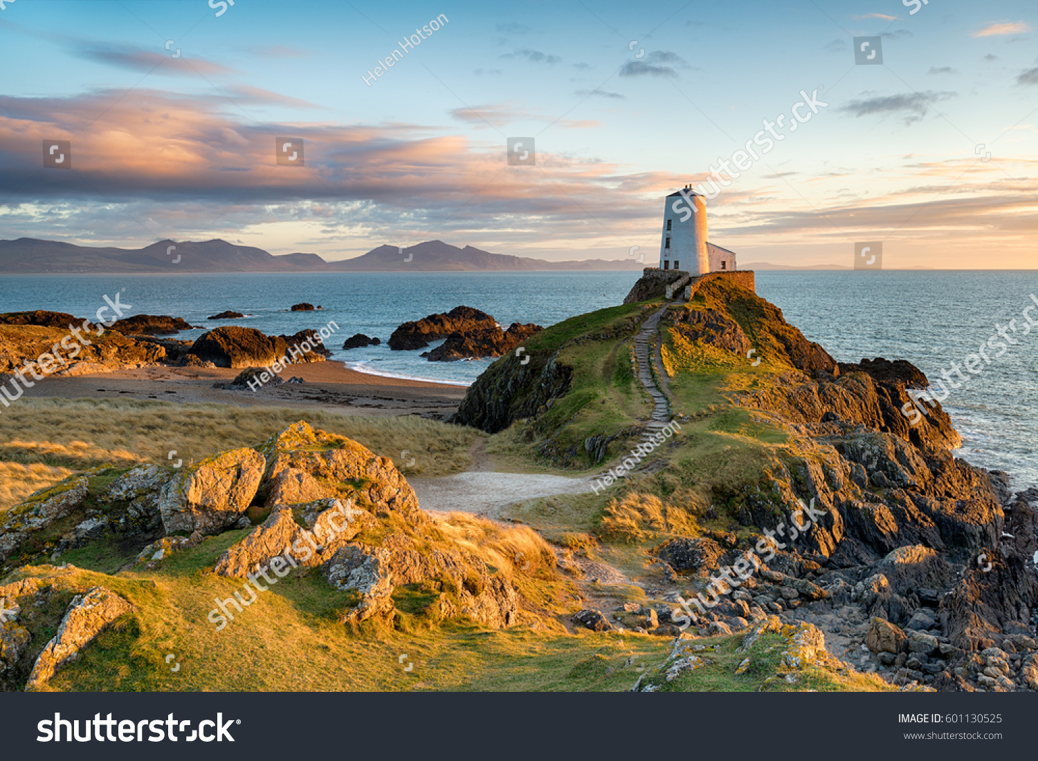 Sunset at Ynys Llanddwyn island on the coast of Anglesey in North Wales with the mountains of Snowdonia in the distance. #601130525