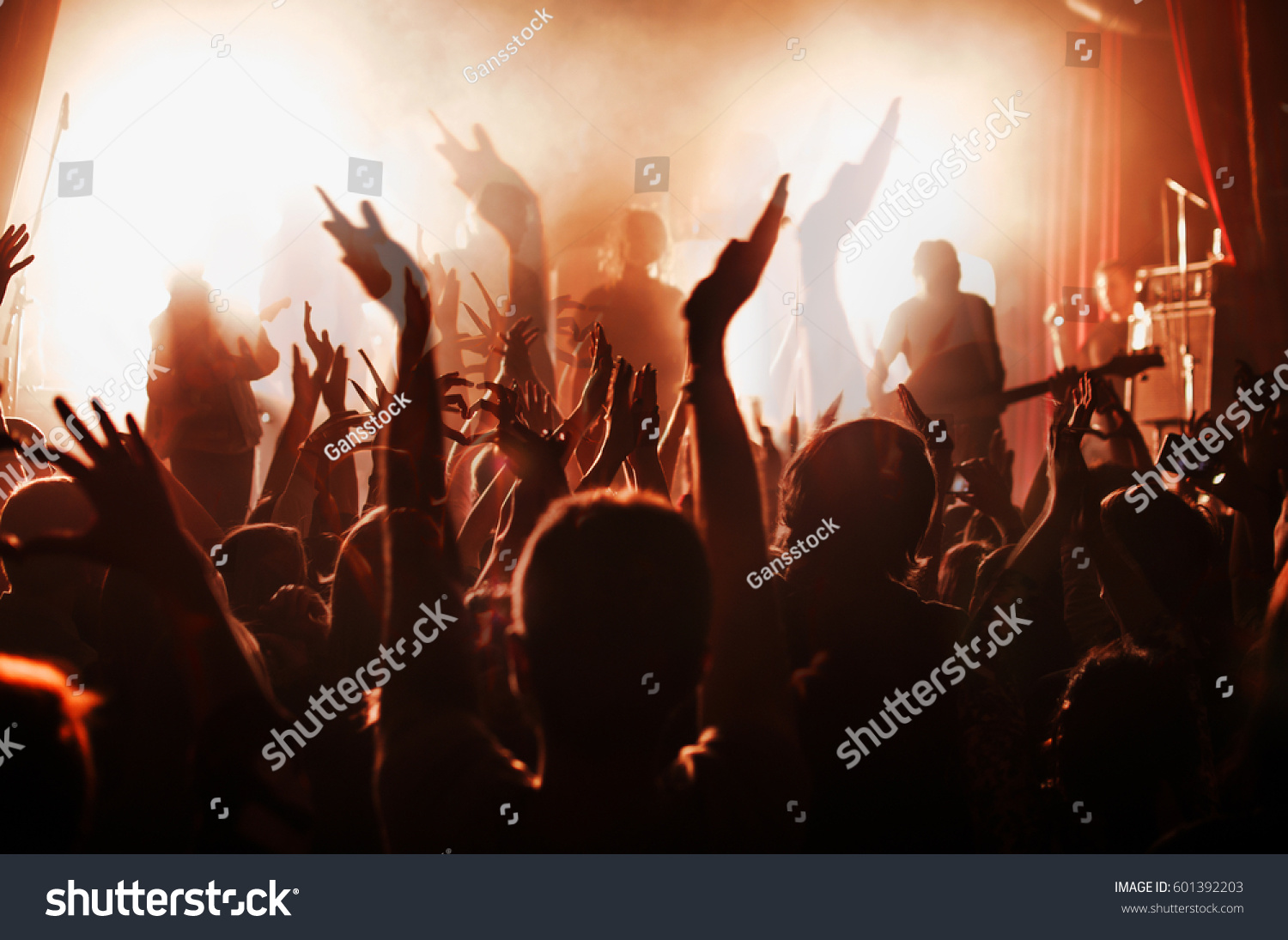 silhouettes of people at a rock festival concert in front of the scene in bright light. Double exposure #601392203