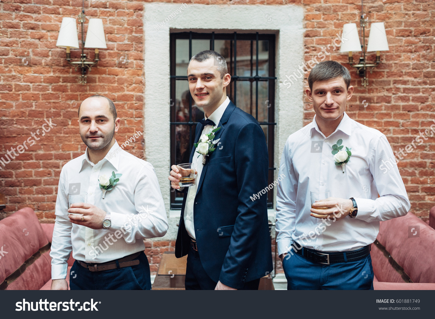Profile of groom and groomsmen drinking whisky in brick hall #601881749