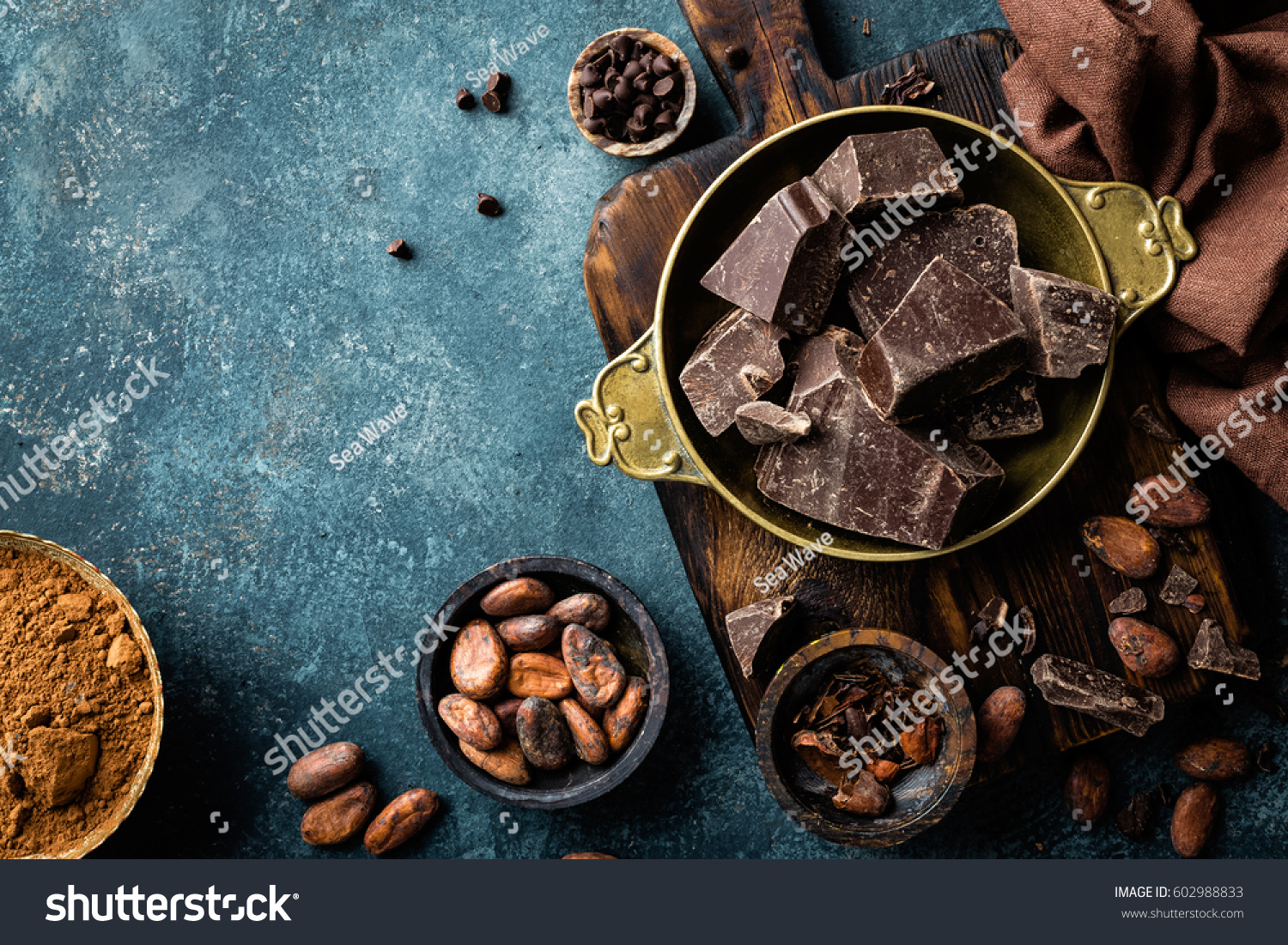 Dark chocolate pieces crushed and cocoa beans, culinary background, top view #602988833
