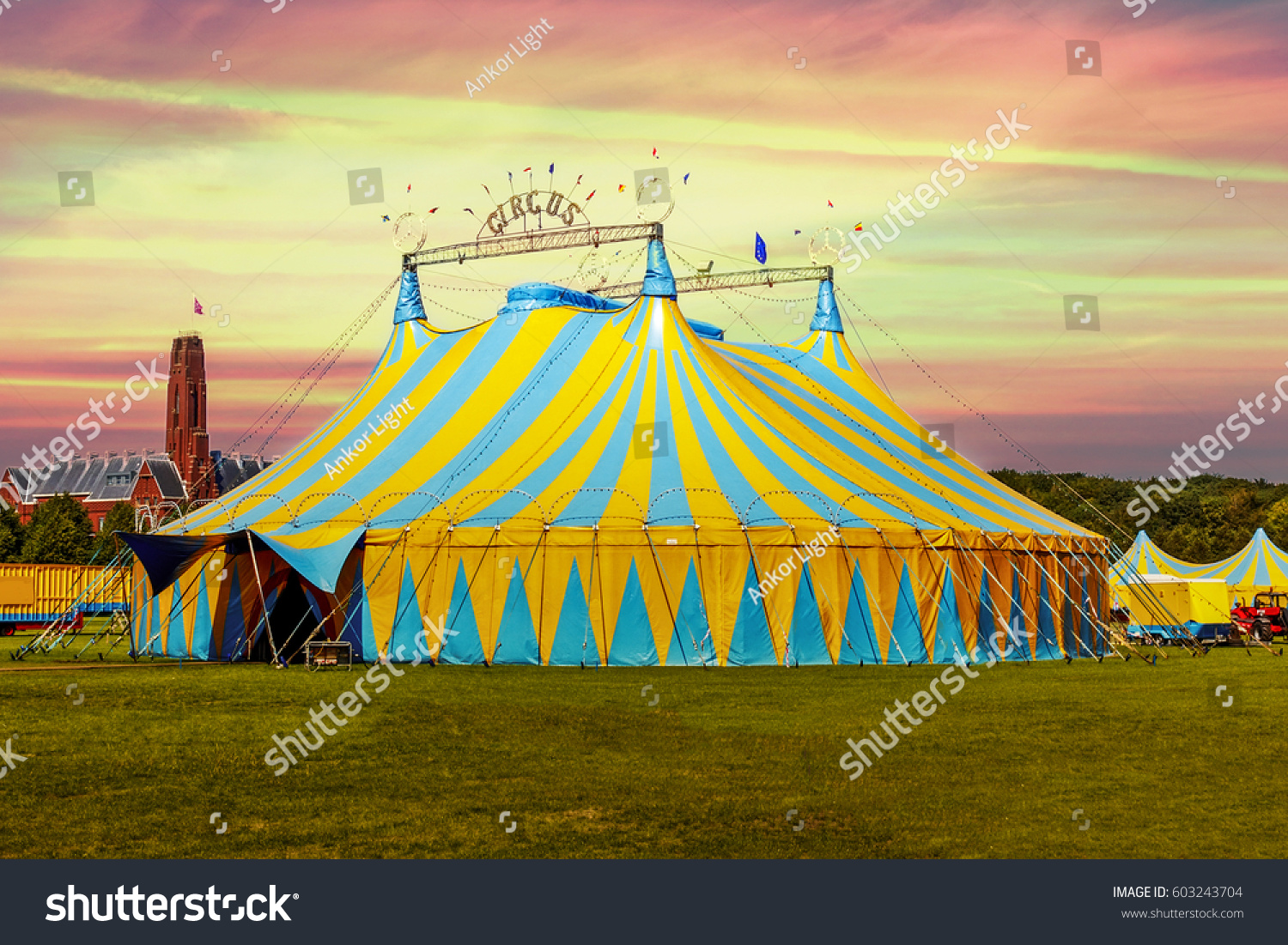 Circus tent under a warn sunset and chaotic sky without the name of the circus company which is cloned out and replaced by the metallic structure #603243704