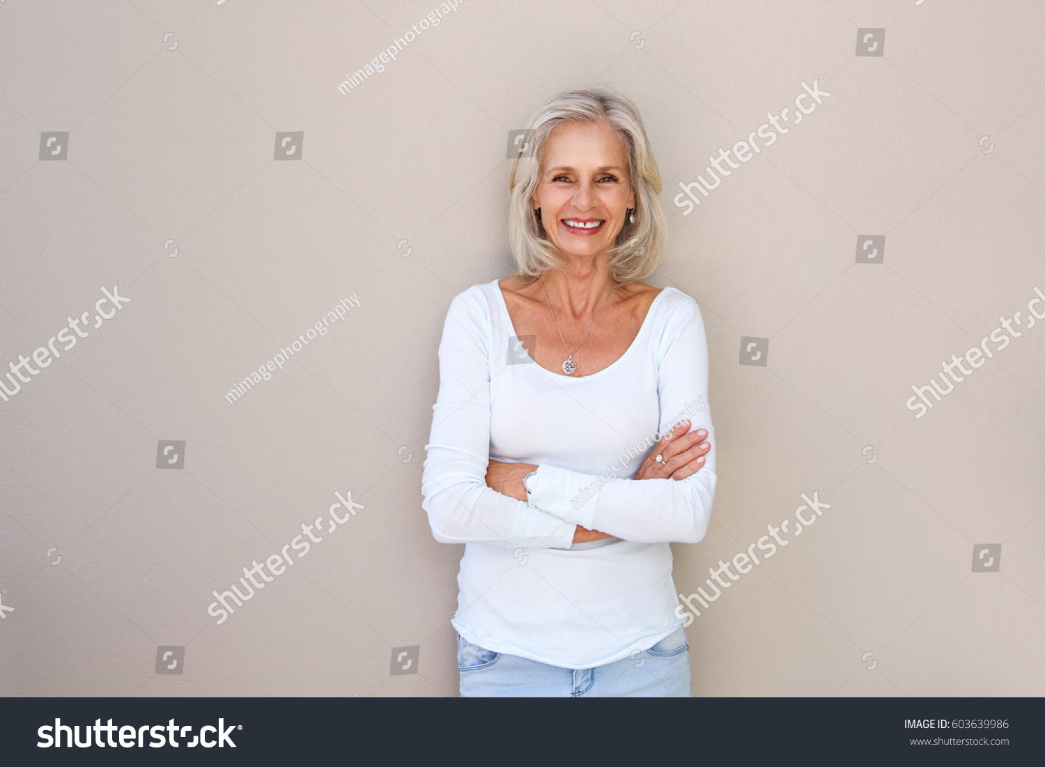 Portrait of beautiful older woman standing and smiling with arms crossed #603639986
