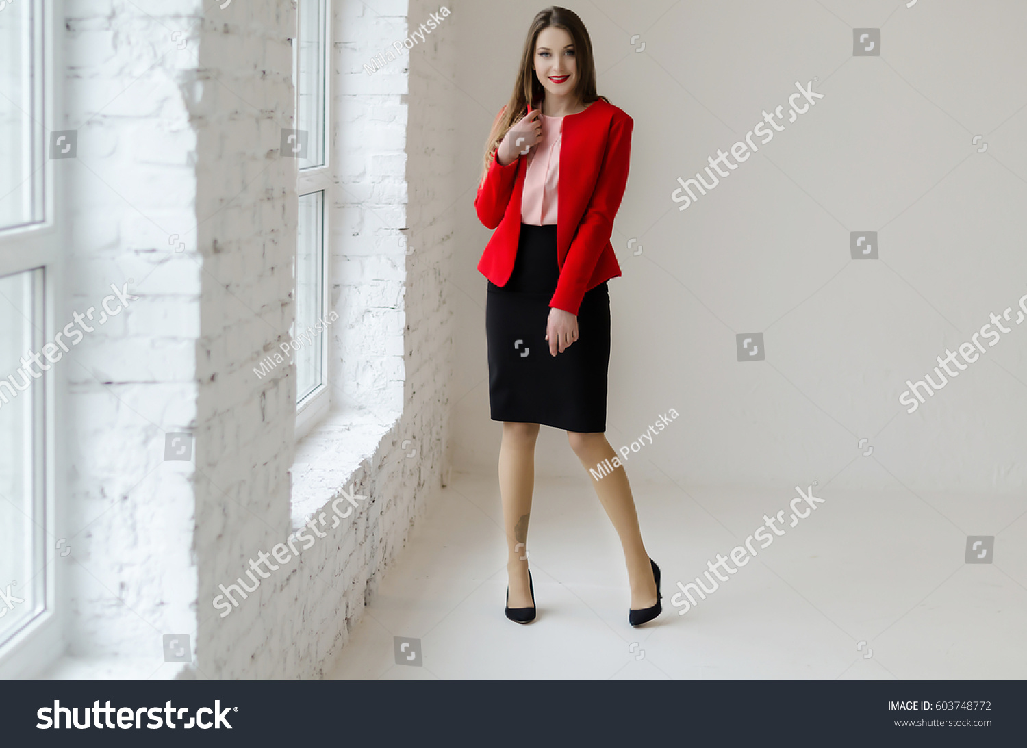 Young woman standing near the window, wearing shirt, jacket and skirt, have a long hair #603748772