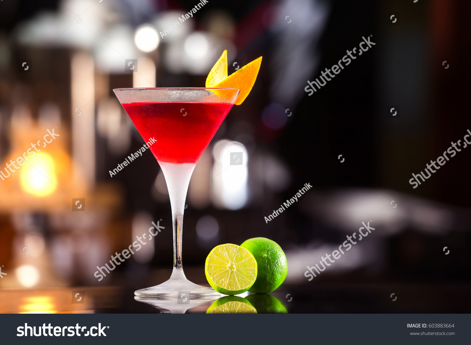 Closeup glass of cosmopolitan cocktail decorated with orange at bar background. #603883664
