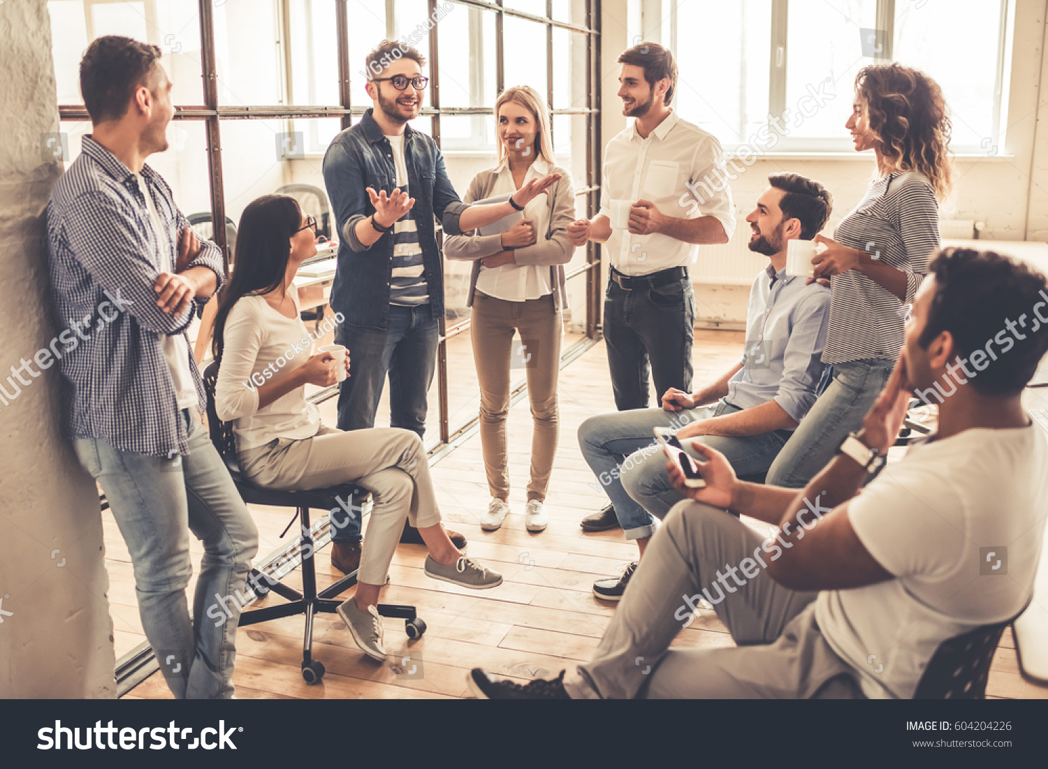 Successful young business people are talking and smiling during the coffee break in office #604204226