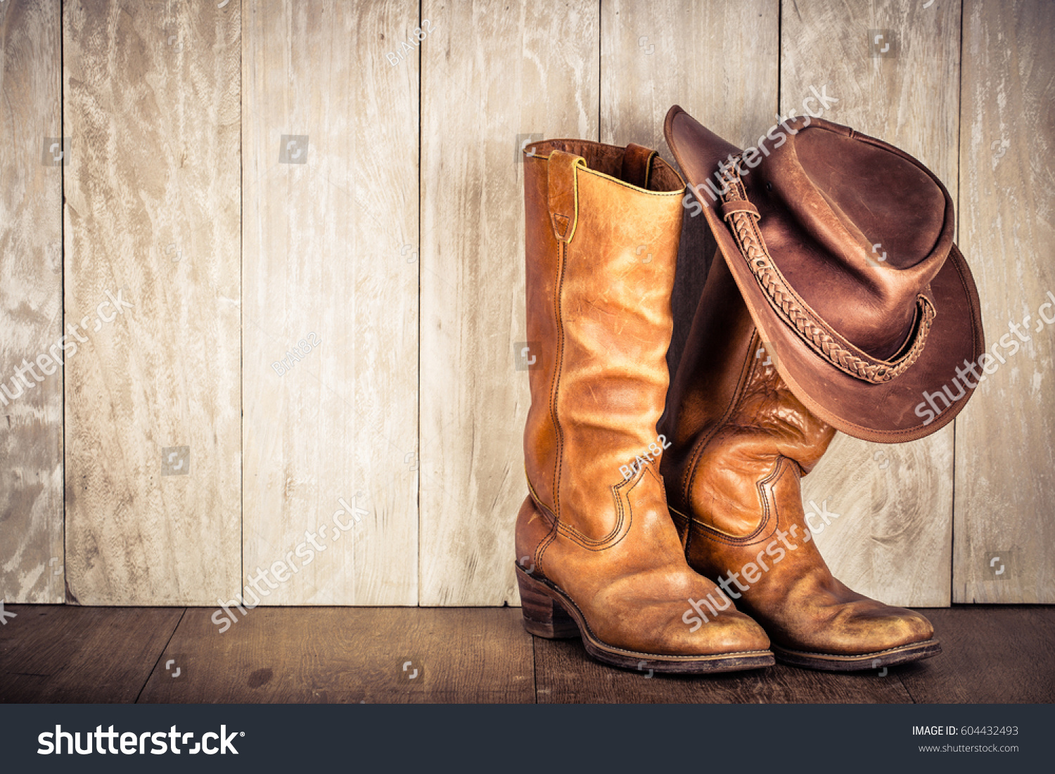 Wild West retro leather cowboy hat and old boots. Vintage style filtered photo #604432493