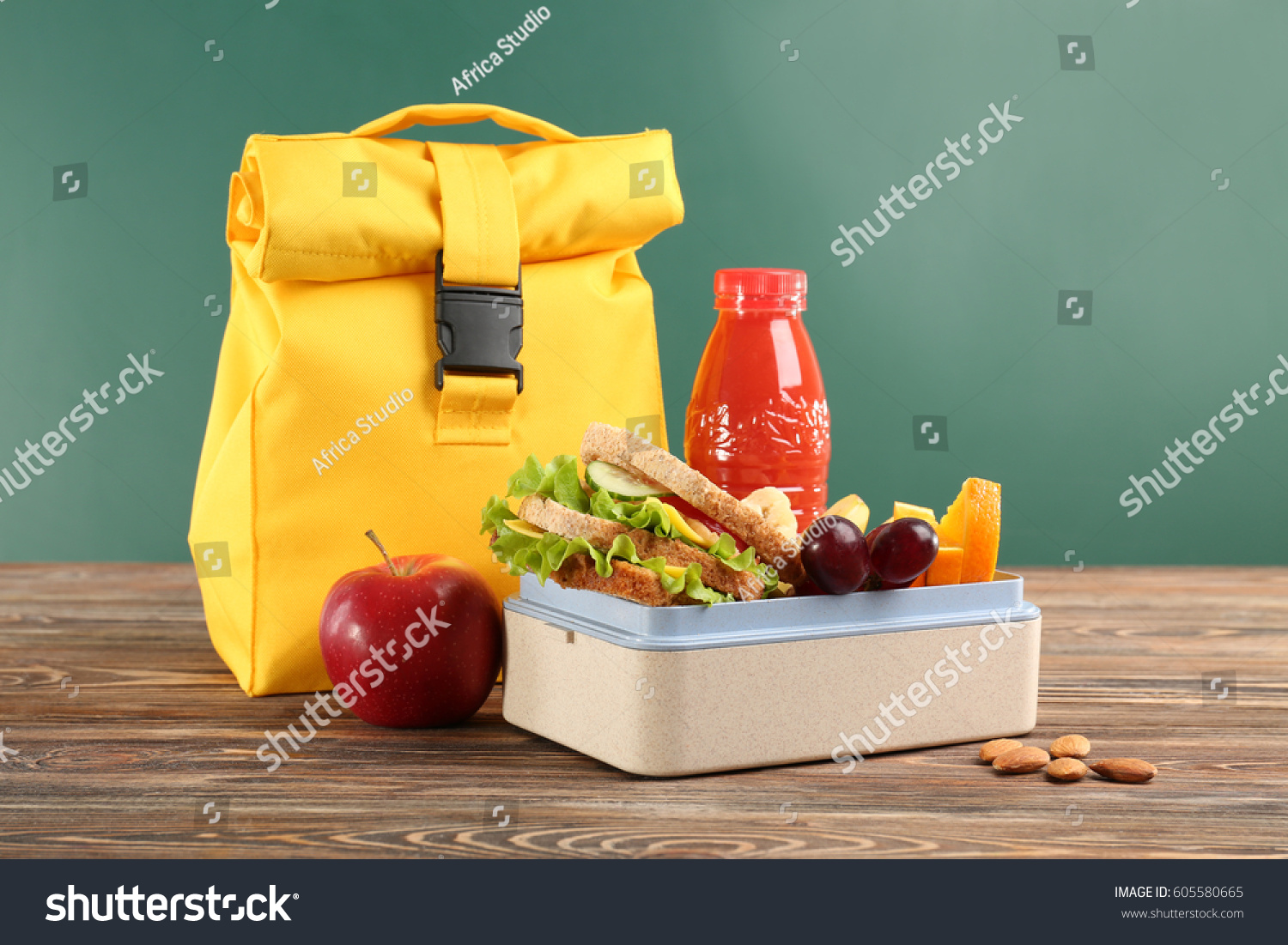 Lunch box with appetizing food and bag on wooden table against chalkboard background #605580665