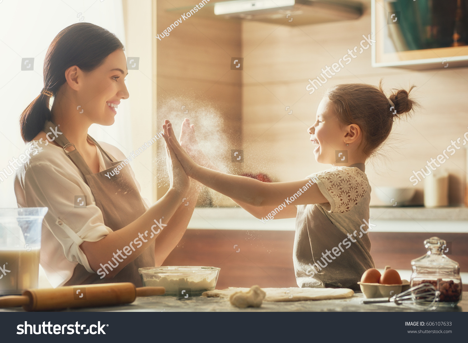 Happy loving family are preparing bakery together. Mother and child daughter girl are cooking cookies and having fun in the kitchen. Homemade food and little helper. #606107633